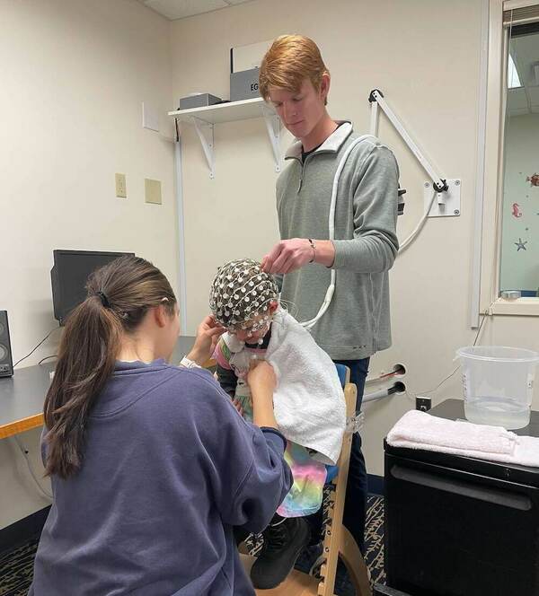 BRAIN Lab research assistant and lab manager EEG capping a child.