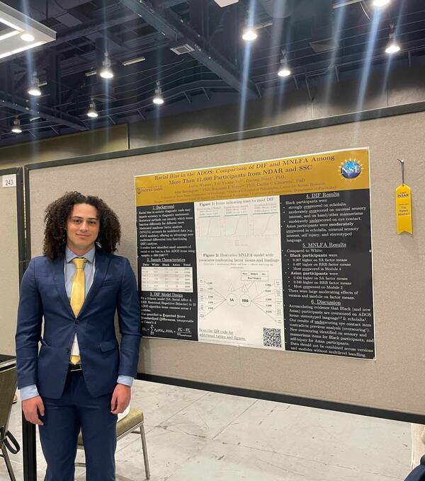 Lab member standing in front of scientific poster.